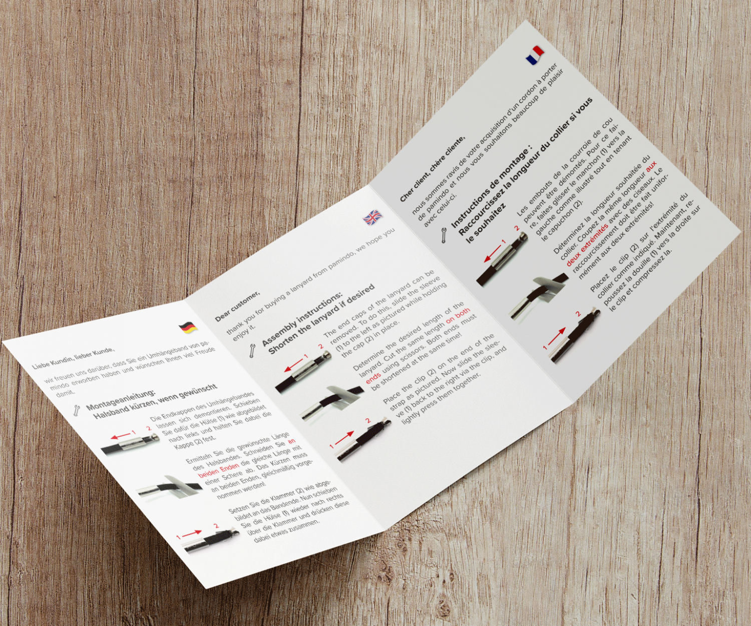 Aufgeschlagener A6 Flyer der eine Montageanleitung für eine Handykette in verschiedenen Sprachen beinhaltet.