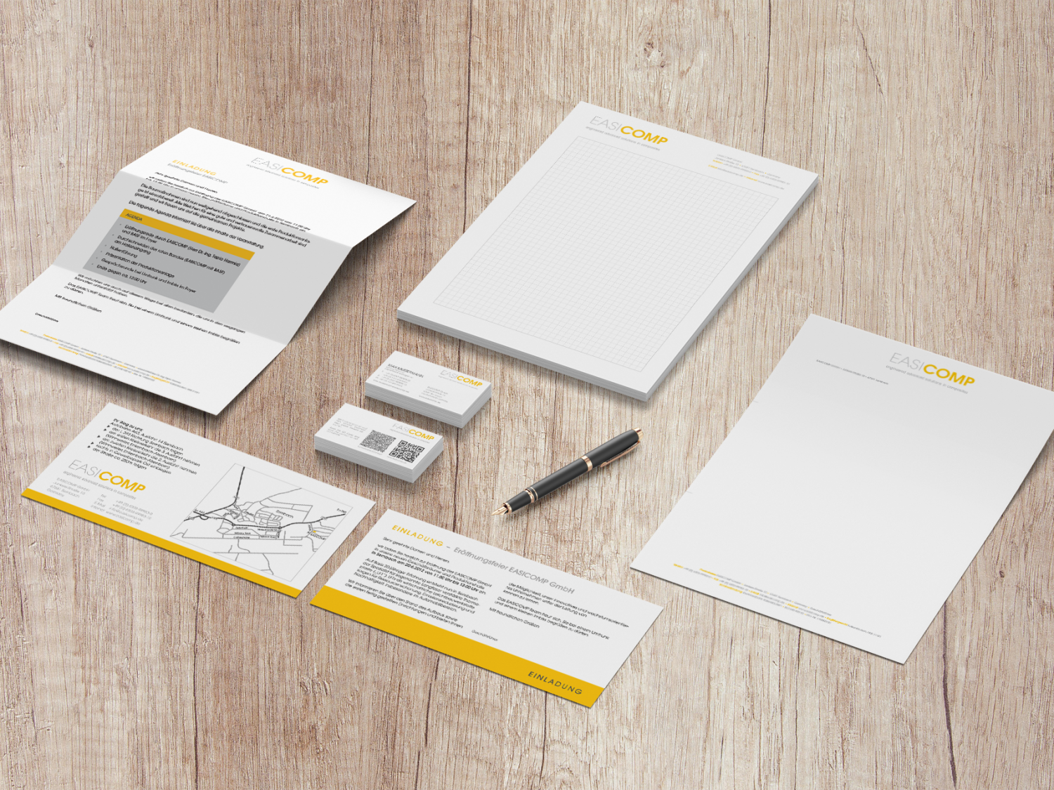 Geschäftspapiere für die EASICOMP GmbH, wie z. B. Rechnungspapier, Visitenkarten, Einladung zur Eröffnung, karierter Schreibblock.