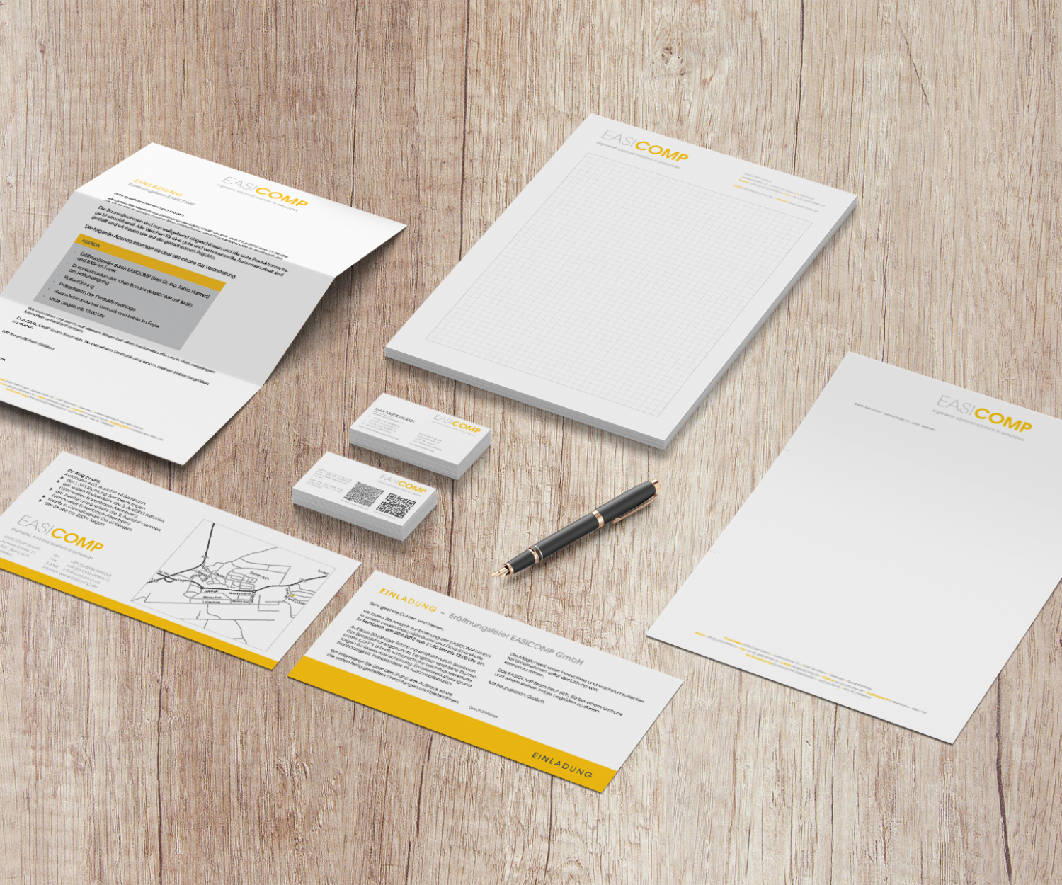 Geschäftspapiere für die EASICOMP GmbH, wie z. B. Rechnungspapier, Visitenkarten, Einladung zur Eröffnung, karierter Schreibblock.